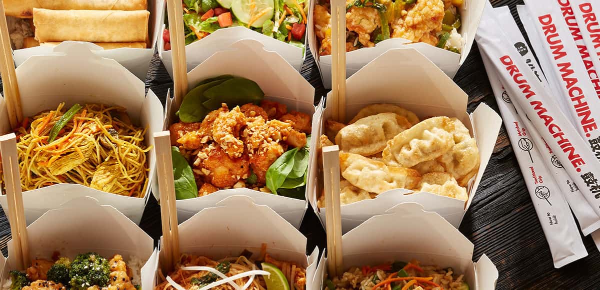 Tin Drum catering boxes filled with Asian noodles, rice, chicken, and dumplings